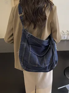 Distressed denim tote bag with contrast stitching and multi-pocket crossbody design