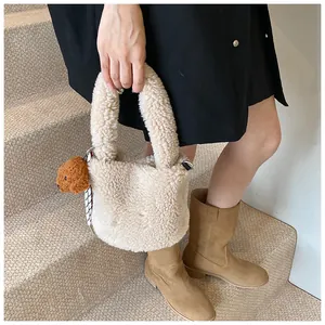 Detail der weißen Sherpa-Eimertasche mit süßem braunem Bären-Plüschanhänger
