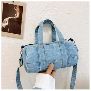 Detail view of light blue denim barrel bag with yellow stitching and silver zipper closure