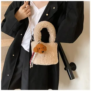 Detailansicht der beigen Plüsch-Beuteltasche mit braunem Pudel-Anhänger und Schultergurt