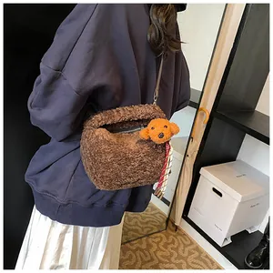 Detail der dunkelbraunen Plüschtasche mit süßem Teddybär-Anhänger an der Schulter