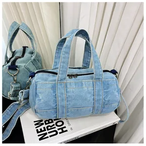 Detailed close-up of light blue denim barrel bag with yellow stitching and metal zipper