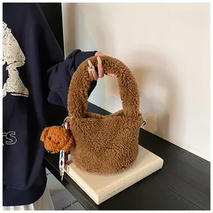 Detail der dunkelbraunen Lammfell-Beuteltasche mit süßem Teddybär-Anhänger auf Buch