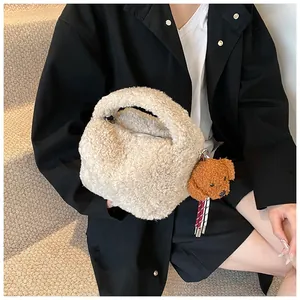Detail der beigen Plüsch-Beuteltasche mit flauschiger Textur und Teddy-Anhänger