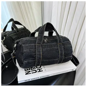 Detail of black denim cylinder bag with yellow contrast stitching on a book