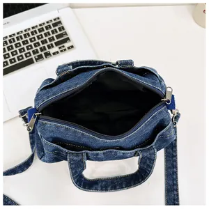 Top view of blue denim crossbody bag showing interior lining and zipper pockets