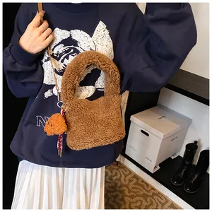 Detail der weichen Plüsch-Beuteltasche in Braun mit Teddy-Anhänger und Leder-Schultergurt