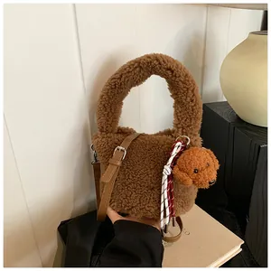 Detailansicht der dunkelbraunen Plüsch-Beuteltasche mit Teddybär-Anhänger und Gurt