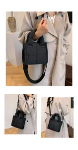 Detail view of quilted black padded crossbody bag with adjustable wide strap and top handle