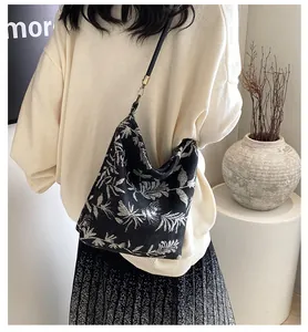 Detail of a vintage-style black bucket bag with silver floral jacquard and bronze buckles