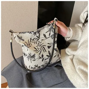 Close-up of vintage embroidered tote bag with dragonfly pattern and gold metal rings