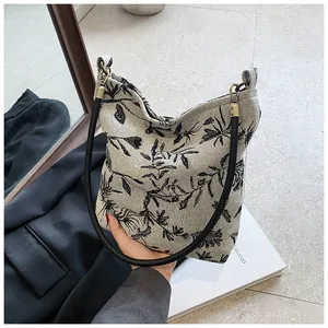 Detailed view of large black leaf patterns on a cream canvas tote bag with slim handles
