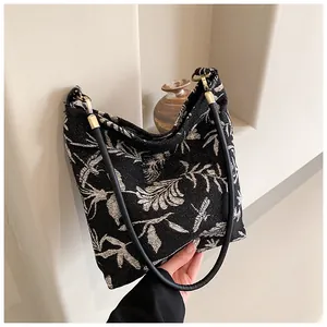 Detail of black canvas tote with white floral pattern and slim shoulder strap