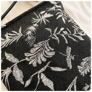 Macro detail of black jacquard fabric with silver dragonfly and leaf embroidery