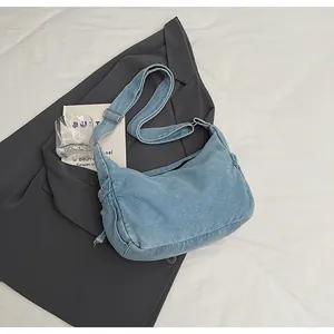 Detail of light blue denim hobo bag with drawstring sides and adjustable shoulder strap