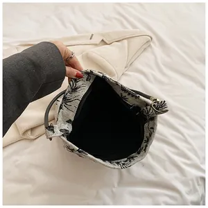 Close-up of canvas handbag with leaf patterns showing zipper closure and black interior