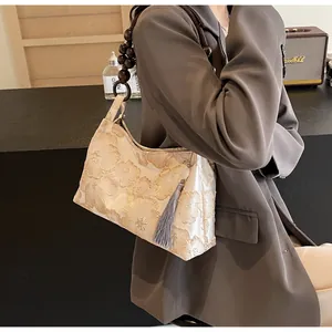 Dettaglio del ricamo floreale e tracolla in perline di legno di un'elegante borsa a mano