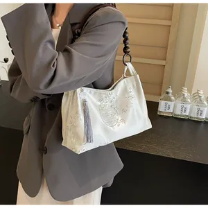 Dettaglio borsa bianca stile cinese con frange in seta e tracolla in perline di legno