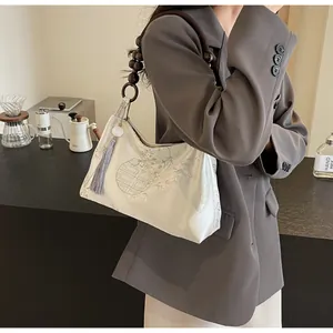 Dettaglio dell'elegante ricamo e della tracolla in legno sulla borsa beige cinese