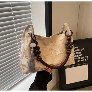 Dettaglio ravvicinato del tessuto ricamato a fiori beige e tracolla in perline di legno