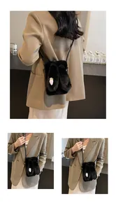 Détail du sac à bandoulière noir en peluche avec oreilles de lapin et broderie carotte rose