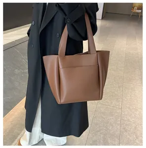 Detail einer braunen Shopper-Tasche mit Außentasche an einem Model in moderner Büro-Umgebung