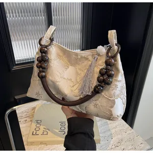 Dettaglio ricamo e manico in perle di legno su borsa a mano etnica bianca vintage