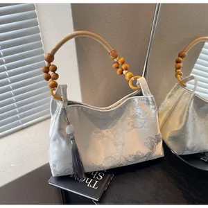 Dettaglio del ricamo e del manico in perle di legno su una borsa a mano vintage