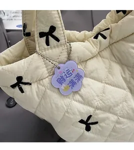 Detail of quilted cream handbag with black bow patterns and a purple floral charm