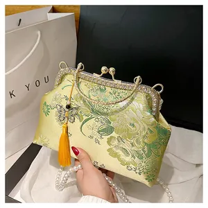 Détails de broderie florale, chaîne de perles et pompon sur sac de soirée en soie