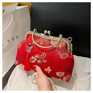 Détail de broderie florale rouge sur sac à main avec poignée perle et pompon décoratif