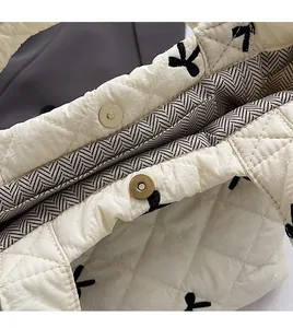 Close-up of diamond quilted fabric with black bow embroidery and vintage magnetic bronze clasp