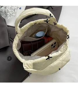Spacious interior of beige quilted handbag showing room for umbrella and phone