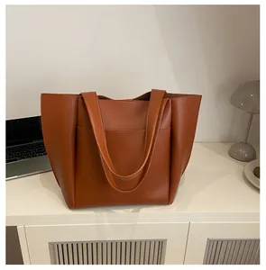 Nahaufnahme der braunen Leder-Tote-Bag mit praktischer Fronttasche auf einem Büroschreibtisch