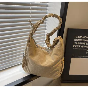 Detail view of the stylish pleated strap and beige padded nylon shoulder bag