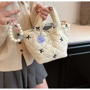 Detail of cream quilted handbag with black bow embroidery and pearl beaded wristlet strap