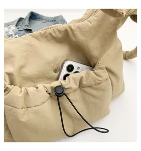 Dettaglio della tasca con coulisse su una borsa trapuntata beige con uno smartphone bianco