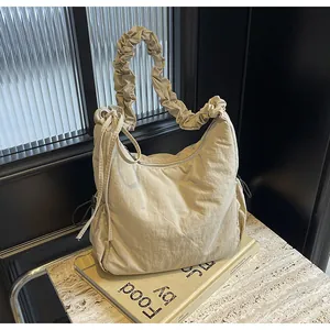 Detailed close-up of beige quilted puffy hobo bag with unique gathered shoulder strap