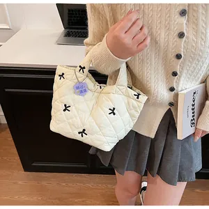 Close-up of quilted cream handbag featuring black bow embroidery and floral charm