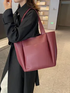 Große weinrote Leder-Shopper-Tasche mit Vordertasche von einem Model auf der Schulter