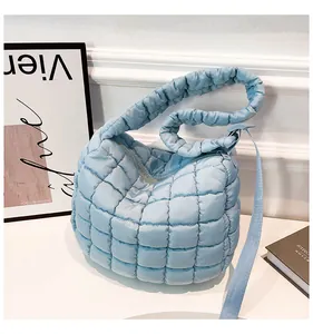 Detail of light blue quilted puffy cloud bag with satin texture and zip closure