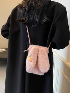 Sac à bandoulière en peluche rose avec broderie carotte porté par un mannequin sur manteau