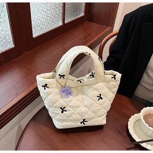 Detail of cream quilted handbag with black bow patterns and purple flower charm