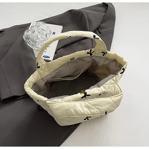 Close-up of cream quilted bucket bag with black bow print and magnetic snap button