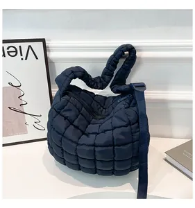 Close-up of the quilted texture and adjustable strap on a dark blue puffer bag