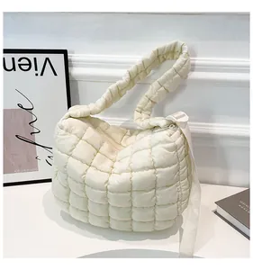 Detailed macro view of quilted puffer texture and zipper on the creamy white shoulder bag