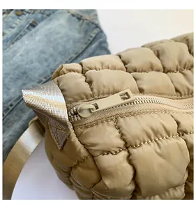 Detailed close-up of beige quilted puffer bag with zip closure and silver chain strap