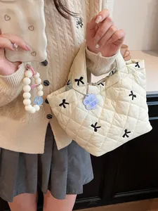 Quilted off-white handbag with bow embroidery and a cute charm accessory