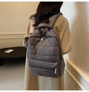 Rear view of a dark grey quilted backpack with silver zippers and padded straps