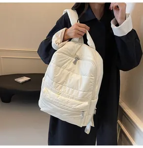 Detailed side view of white quilted padded backpack showing soft puffer texture and zippers